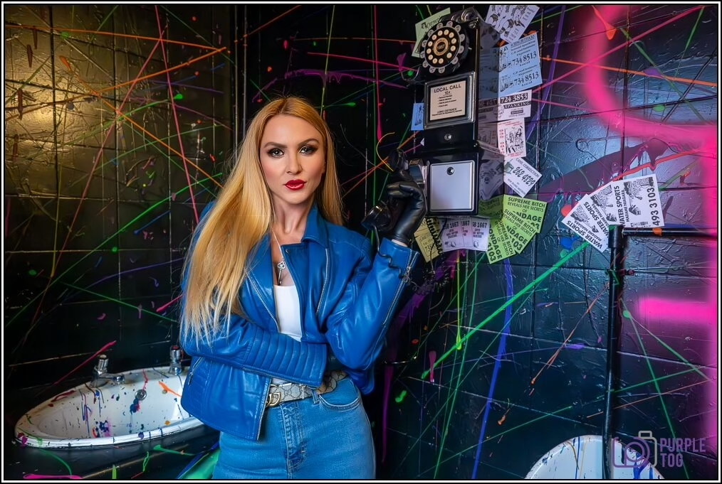 A performer in a blue leather jacket beside a vintage payphone, shot at Maxwell Manor