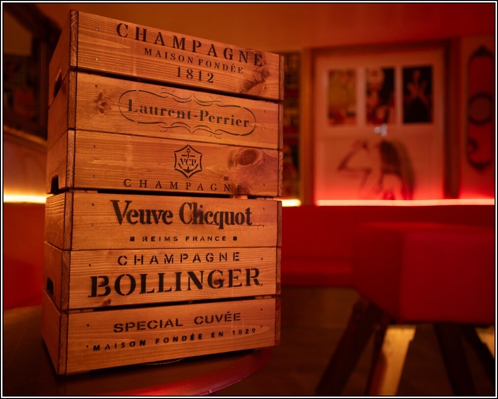 Stacked vintage champagne crates in the Club’s red-lit lounge